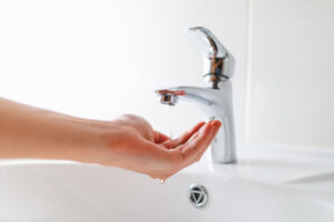 hand under faucet with low pressure water stream, close-up view